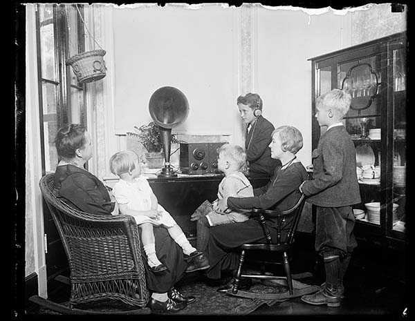 Familie samlet omkring et radioapparat med hornhøjttaler i 1921